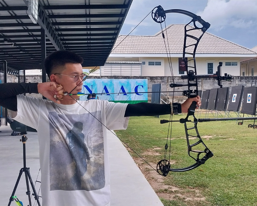 A member of NAAC stands with a compound bow, ready to shoot, practicing on his form.